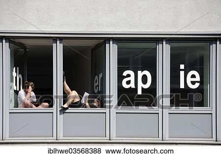 Stock Photo - "Students of a school for physical therapy taking a break and reading at windows with the word """"therapie"""", Hamburg, Hamburg, Germany, Europe". Fotosearch