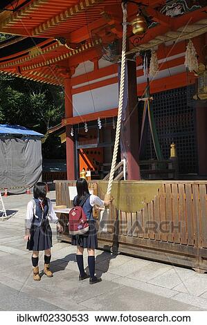 Stock Image - "Students wearing school uniforms ringing the bell on a shrine to draw the spirits' attention to them, Yasaka Shrine, Maruyama Park, Kyoto, Japan, East Asia, Asia". Fotosearch