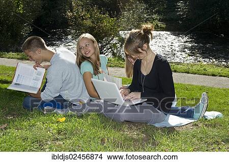 Picture - "Students with a laptop and books on a meadow, Freiburg im Breisgau, Baden-Wuerttemberg, Germany, Europe". Fotosearch