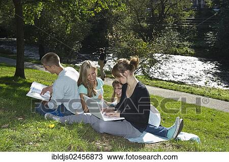 Stock Image - "Students with laptops and books on a meadow, Freiburg im Breisgau, Baden-Wuerttemberg, Germany, Europe". Fotosearch