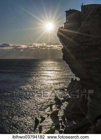 Stock Image - "Sun over the Mediterranean Sea, cliffs with houses, backlit, Bonifacio, Corsica, France, Europe". Fotosearch