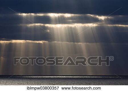 Stock Photo - "Sun rays shine through dark storm clouds, Fuerteventura, Canary Islands, Spain, Europe". Fotosearch