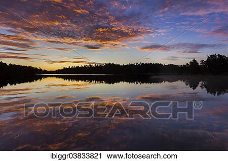 Stock Image - "Sunrise at a lake, near Ed, Dalsland, Vastra Gotaland, Sweden, Europe". Fotosearch