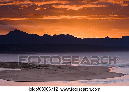 Stock Image - "Sunrise on the coast of the Indian Ocean, mountain ridge, Plettenberg Bay or Plettenbergbaai, Garden Route, Eden District, Western Cape, South Africa, Africa". Fotosearch