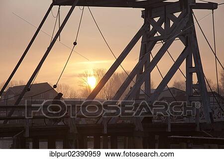 Stock Photo - "Sunrise with mist at Wiecker Bridge and harbour, Wieck district, Greifswald, Mecklenburg-Western Pomerania, Germany, Europe". Fotosearch