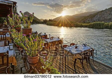 "Sunset, set tables in a restaurant on the Dalyan River, Dalyan, Mugla Province, Turkish Riviera or Turquoise Coast, Aegean, Turkey, Asia" View Large Photo Image Stock Image - "Sunset, set tables in a restaurant on the Dalyan River, Dalyan, Mugla Province, Turkish Riviera or Turquoise Coast, Aegean, Turkey, Asia". Fotosearch