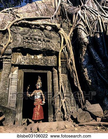 Stock Image - "Ta Prohm temple overgrown with huge roots of Tetrameles nudiflora, temple dancer or apsara in the courtyard, UNESCO World Cultural Heritage Site, Siem Reap, Siem Reap Province, Cambodia, Asia". Fotosearch