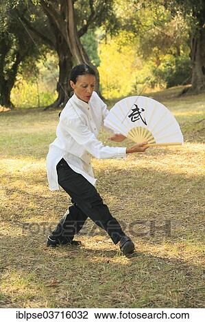 Stock Image - "Tai Chi performed with a fan, demonstration in an olive grove, Regine Zanini, two-time silver medalist of the Tai Chi European Championships 2012, Menton, French Riviera, Alpes-Maritimes, Provence-Alpes-Cote dâ€™Azur, France, Europe". Fotosearch