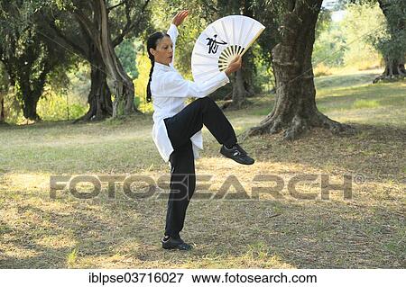 Stock Photo - "Tai Chi performed with a fan, demonstration in an olive grove, Regine Zanini, two-time silver medalist of the Tai Chi European Championships 2012, Menton, French Riviera, Alpes-Maritimes, Provence-Alpes-Cote dâ€™Azur, France, Europe". Fotosearch
