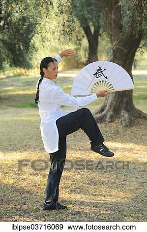 Stock Photo - "Tai Chi performed with a fan, demonstration in an olive grove, Regine Zanini, two-time silver medalist of the Tai Chi European Championships 2012, Menton, French Riviera, Alpes-Maritimes, Provence-Alpes-Cote dâ€™Azur, France, Europe". Fotosearch
