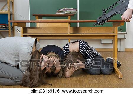 "Teacher and school children crouching under a desk in front of a gunman, Germany, Europe" View Large Photo Image Stock Photograph - "Teacher and school children crouching under a desk in front of a gunman, Germany, Europe". Fotosearch