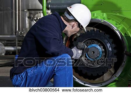 Technician attaching the connecting gear-wheel of an electric generator with an impact wrench View Large Photo Image Picture - Technician attaching the connecting gear-wheel of an electric generator with an impact wrench. Fotosearch