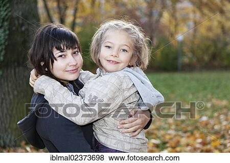 Stock Photo - "Teenage girl, 14 years, holding girl, 6 years, in her arms". Fotosearch