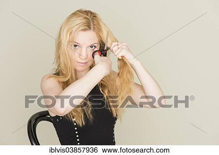 Teenage girl cutting her hair with scissors View Large Photo Image Stock Photograph - Teenage girl cutting her hair with scissors. Fotosearch