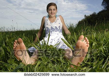 Teenage girl wearing a dress sitting with bare feet in the grass View Large Photo Image Stock Photo - Teenage girl wearing a dress sitting with bare feet in the grass. Fotosearch