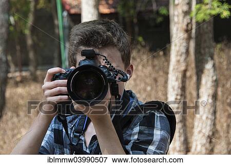 Teenager taking a photo with a professional camera View Large Photo Image Stock Photo - Teenager taking a photo with a professional camera. Fotosearch