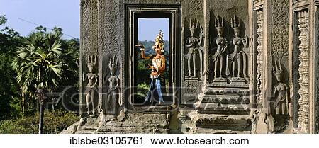 Stock Image - "Temple dancer or apsara in a window of the temple of Angkor Wat beside apsara reliefs, UNESCO World Cultural Heritage Site, Siem Reap, Siem Reap Province, Cambodia, Asia". Fotosearch