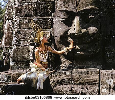 "Temple dancer or apsara sitting in front of a face tower at Bayon Temple, UNESCO World Cultural Heritage Site, Angkor Thom, Siem Reap, Siem Reap Province, Cambodia, Asia" View Large Photo Image Stock Photo - "Temple dancer or apsara sitting in front of a face tower at Bayon Temple, UNESCO World Cultural Heritage Site, Angkor Thom, Siem Reap, Siem Reap Province, Cambodia, Asia". Fotosearch