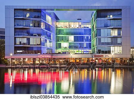 "The colourfully lit """"H2 Office"""" building with restaurants at dusk, Innenhafen, Inner Harbour, Duisburg, Ruhr Area, North Rhine-Westphalia, Germany, Europe" View Large Photo Image Stock Photography - "The colourfully lit """"H2 Office"""" building with restaurants at dusk, Innenhafen, Inner Harbour, Duisburg, Ruhr Area, North Rhine-Westphalia, Germany, Europe". Fotosearch