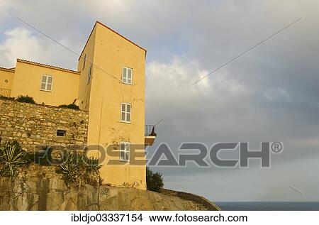 "The facade of a yellow house with windows and a balcony in the citadel of Calvi below a cloudy sky. Calvi is in the department Haute-Corse, France on the mediterranean island of Corsica, Calvi, Corsica, France, Europe" View Large Photo Image Picture - "The facade of a yellow house with windows and a balcony in the citadel of Calvi below a cloudy sky. Calvi is in the department Haute-Corse, France on the mediterranean island of Corsica, Calvi, Corsica, France, Europe". Fotosearch