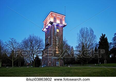 Stock Image - "The illuminated Hammerkopfturm tower of Zeche Erin Colliery at dusk, Castrop-Rauxel, Ruhr Area, North Rhine-Westphalia, Germany, Europe". Fotosearch