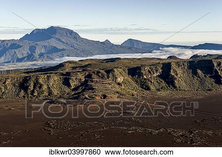 Stock Image - "The Piton des Neiges volcano rising behind a road to the Piton de la Fournaise volcano, Reunion, Africa". Fotosearch