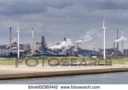 Stock Image - "The sandy beach near Wijk aan Zee with beach pavilions, wind turbines and the Tata steel plant at the back, North Holland, the Netherlands, Europe". Fotosearch