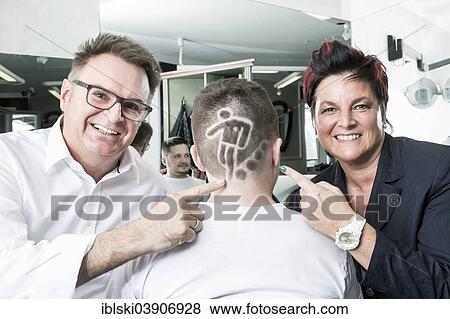 Stock Photo - "The two hairdressers Gerhard Ostler and Sylvia Ostler posing with a customer who has received a Football World Cup hair tattoo from them, Worth an der Donau, Bavaria, Germany, Europe". Fotosearch