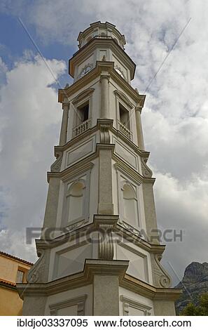 Stock Photography - "The white tower of the church of the small village Calenzana in front of a cloudy sky. Calenzana is in the western part of the mediterranean island Corsica, France, Calenzana, Corsica, France, Europe". Fotosearch
