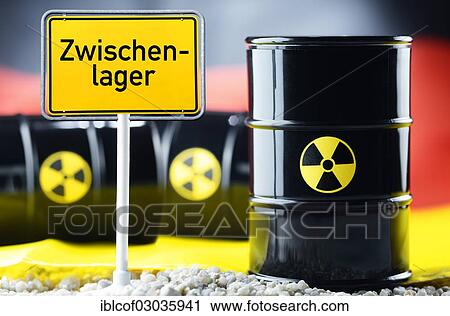 Stock Image - "Three barrels of nuclear waste in front of a German flag and a town sign with the name """"Zwischenlager"""", German for interim storage, Germany, Europe". Fotosearch