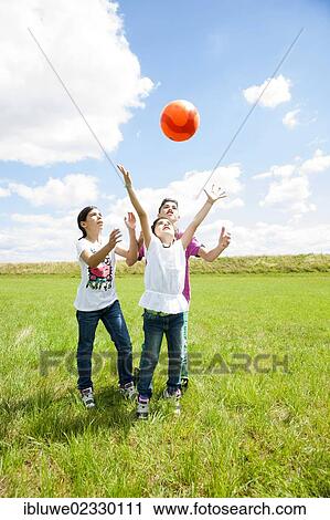 Three children playing ball on a meadow View Large Photo Image Stock Image - Three children playing ball on a meadow. Fotosearch