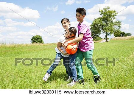 Three children playing ball on a meadow View Large Photo Image Stock Photography - Three children playing ball on a meadow. Fotosearch