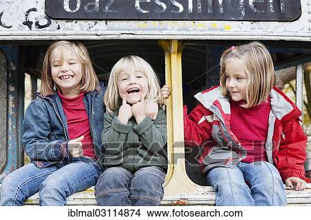 Picture - "Three children sitting in a disused bus, Esslingen, Baden-Wurttemberg, Germany, Europe". Fotosearch