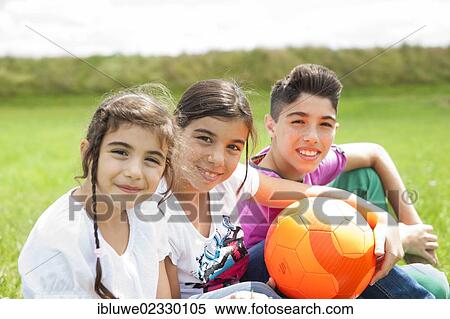 Three children sitting on a meadow View Large Photo Image Stock Photography - Three children sitting on a meadow. Fotosearch