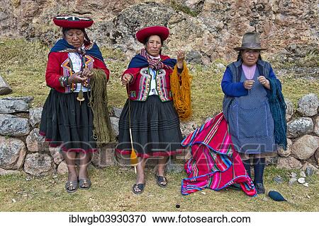 Stock Image - "Three elderly women wearing hats, Quechua Indians in traditional dress spinning wool with wooden spindles, Cinchero, Urubamba Valley, Peru, South America". Fotosearch