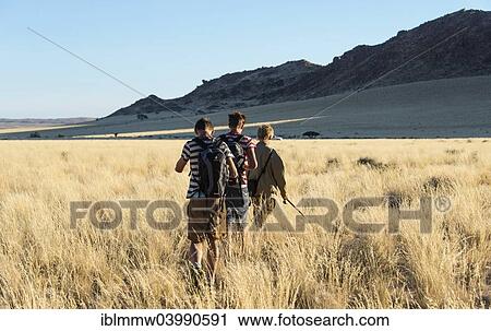 Stock Image - "Three hikers at the Naukluft Mountains, Namib-Naukluft, Namibia, Africa". Fotosearch