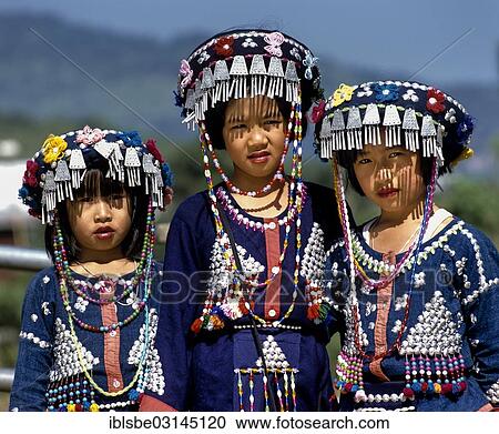 Stock Image - "Three Lisu girls wearing colourful headdresses and the traditional costume of the mountain people, Mae Sai, Chiang Rai Province, Northern Thailand, Thailand, Asia". Fotosearch