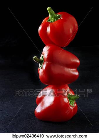Stock Image - Three red peppers balancing on each other. Fotosearch