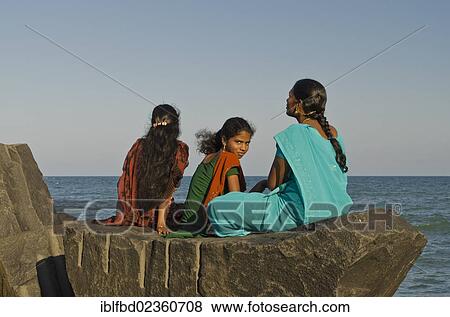 "Three young ladies sitting on a rock at the beach of Pondicherry, looking out to the sea, Pondicherry, India, Asia" View Large Photo Image Stock Photo - "Three young ladies sitting on a rock at the beach of Pondicherry, looking out to the sea, Pondicherry, India, Asia". Fotosearch