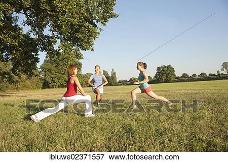 Three young women doing gymnastics exercises together in a meadow View Large Photo Image Stock Photo - Three young women doing gymnastics exercises together in a meadow. Fotosearch