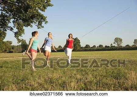 Three young women doing gymnastics exercises together in a meadow View Large Photo Image Stock Photograph - Three young women doing gymnastics exercises together in a meadow. Fotosearch