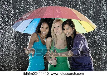 "Three young women of Indian, Cuban and European descent, standing together under a rainbow-coloured umbrella while enjoying the rain" View Large Photo Image Stock Image - "Three young women of Indian, Cuban and European descent, standing together under a rainbow-coloured umbrella while enjoying the rain". Fotosearch