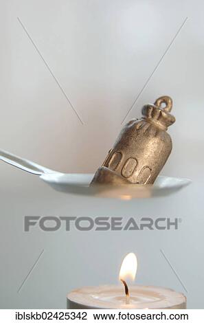 Stock Image - Tin or lead being molten before it is dropped into cold water from which the future is read on New Year's Eve. Fotosearch