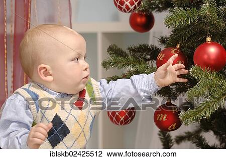Toddler reaching for baubles on a Christmas tree View Large Photo Image Stock Image - Toddler reaching for baubles on a Christmas tree. Fotosearch