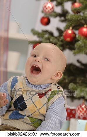 Stock Photo - Toddler singing in front of a Christmas tree. Fotosearch