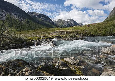 Stock Photo - "Torrent foaming between boulders in front of an alm or alpine meadow with huts and mountains, Skjaeringsdalsseter, Grasdal, Reichsstrasse 15, Sogn og Fjordane, Western Norway, Norway, Europe". Fotosearch