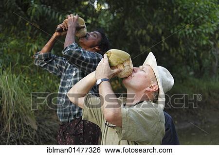 Stock Photograph - "Tourist and an Indian man drinking from a coconut, Kerala, South India, India, Asia". Fotosearch
