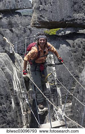 "Tourist crossing a suspension bridge in the Great Tsingy de Bemaraha limestone formations, UNESCO World Natural Heritage Site, Tsingy de Bemaraha National Park, Melaky Region, Madagascar, Africa" View Large Photo Image Stock Image - "Tourist crossing a suspension bridge in the Great Tsingy de Bemaraha limestone formations, UNESCO World Natural Heritage Site, Tsingy de Bemaraha National Park, Melaky Region, Madagascar, Africa". Fotosearch