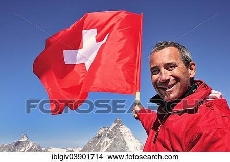 "Tourist holding a Swiss flag over the Matterhorn, 4478 m, Klein Matterhorn, Zermatt, Canton of Valais, Switzerland, Europe" View Large Photo Image Picture - "Tourist holding a Swiss flag over the Matterhorn, 4478 m, Klein Matterhorn, Zermatt, Canton of Valais, Switzerland, Europe". Fotosearch