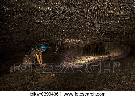Stock Image - "Tourist in a subterranean lava tube created by an eruption of the Piton de la Fournaise volcano, Le Grand Brule, Reunion, Africa". Fotosearch
